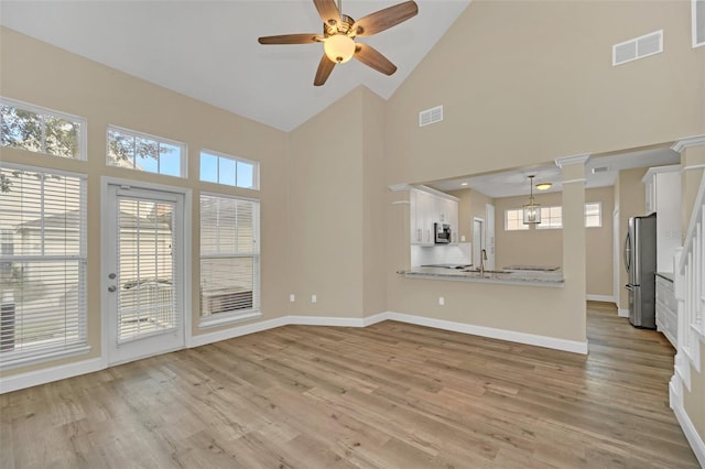 unfurnished living room with plenty of natural light, high vaulted ceiling, and light wood-type flooring