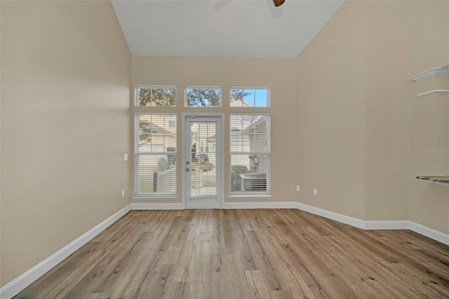 empty room featuring ceiling fan, high vaulted ceiling, and light hardwood / wood-style flooring