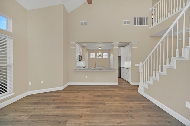 unfurnished living room featuring wood-type flooring and high vaulted ceiling