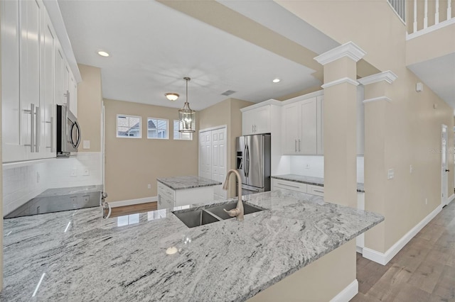 kitchen with appliances with stainless steel finishes, light stone counters, sink, light hardwood / wood-style flooring, and white cabinetry