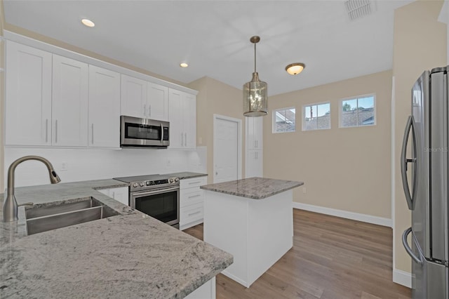 kitchen with sink, a center island, light stone countertops, and appliances with stainless steel finishes