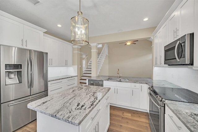 kitchen featuring sink, stainless steel appliances, white cabinets, ceiling fan with notable chandelier, and light wood-type flooring