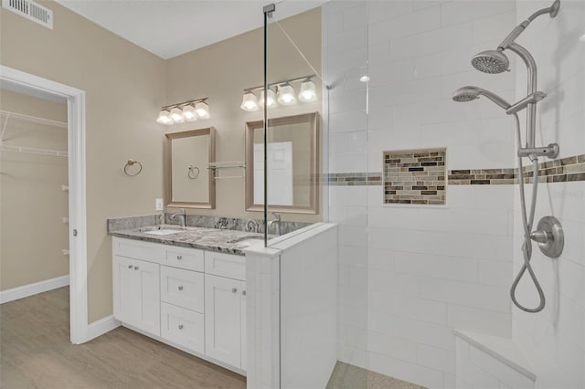 bathroom with vanity, a tile shower, and wood-type flooring