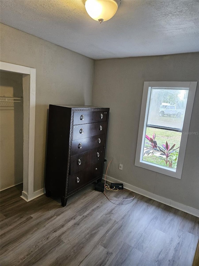 unfurnished bedroom featuring wood-type flooring, a textured ceiling, and a closet