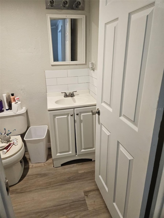 bathroom featuring decorative backsplash, hardwood / wood-style floors, vanity, and toilet