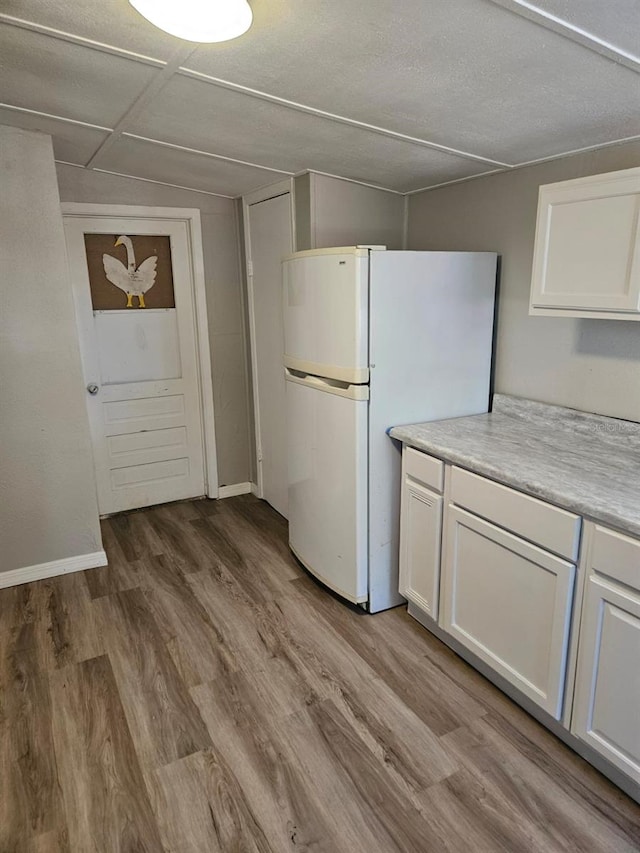 kitchen with light hardwood / wood-style floors, white fridge, and white cabinetry