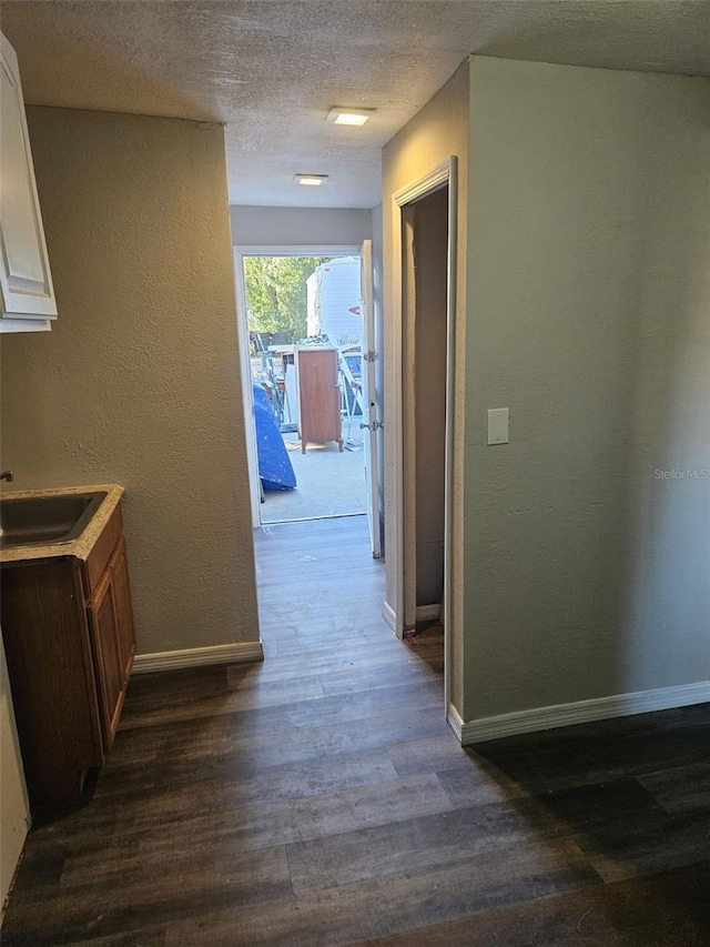 corridor featuring a textured ceiling, dark hardwood / wood-style floors, and sink