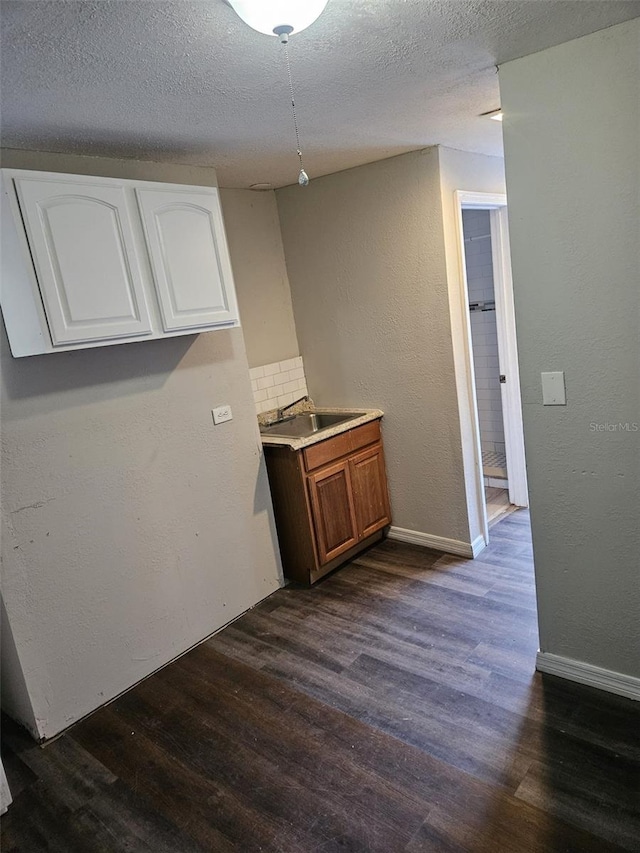 interior space with a textured ceiling, sink, and dark hardwood / wood-style floors