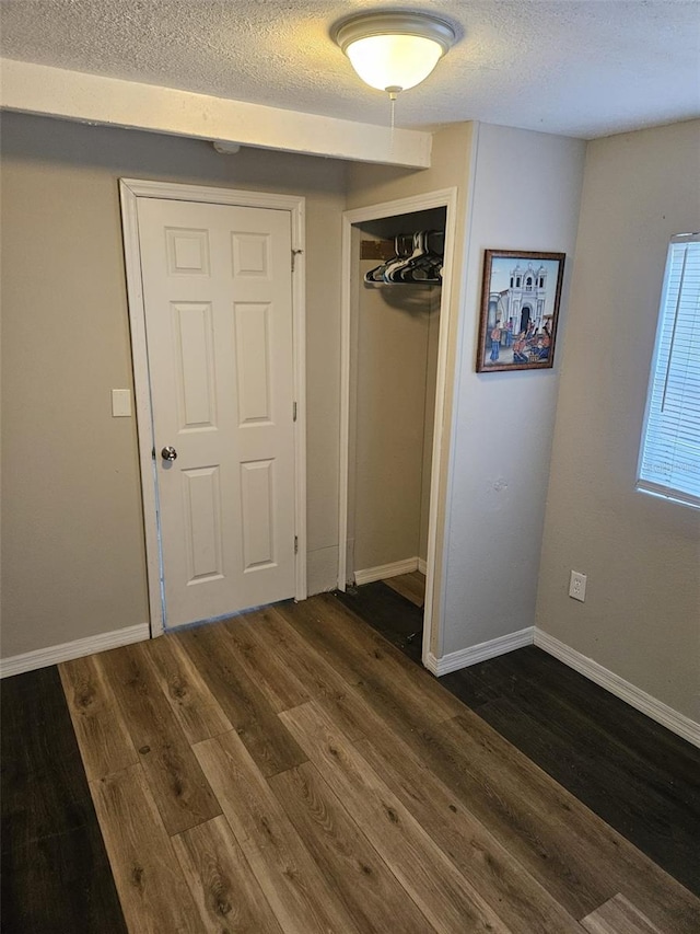 unfurnished bedroom with a closet, dark wood-type flooring, and a textured ceiling