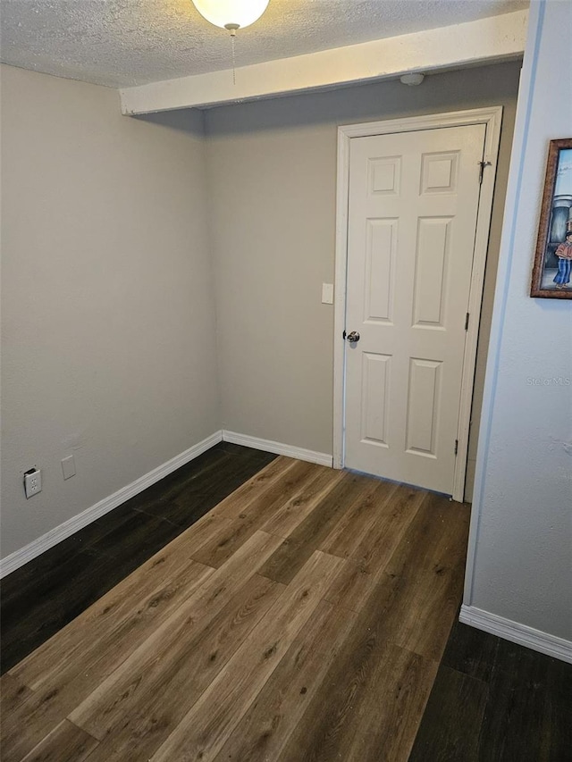 unfurnished room with a textured ceiling and dark wood-type flooring