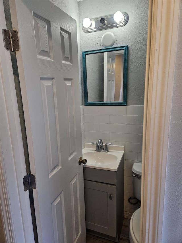 bathroom featuring vanity, toilet, tile walls, and tasteful backsplash