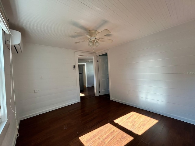 empty room with a wall mounted AC, ceiling fan, and dark hardwood / wood-style flooring