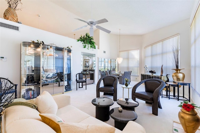 carpeted living room featuring a towering ceiling and ceiling fan