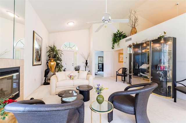 carpeted living room featuring ceiling fan, a tile fireplace, and high vaulted ceiling