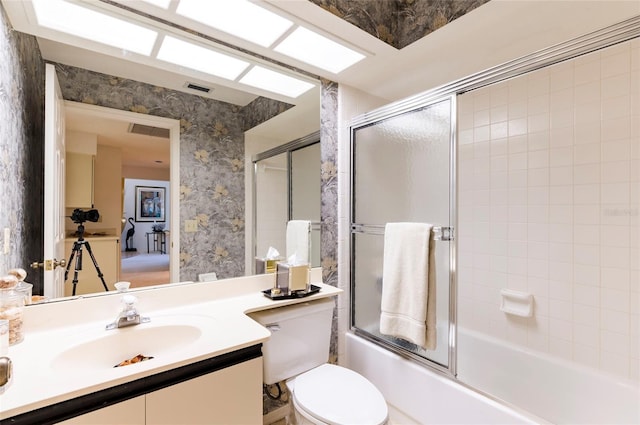 full bathroom featuring combined bath / shower with glass door, vanity, and toilet