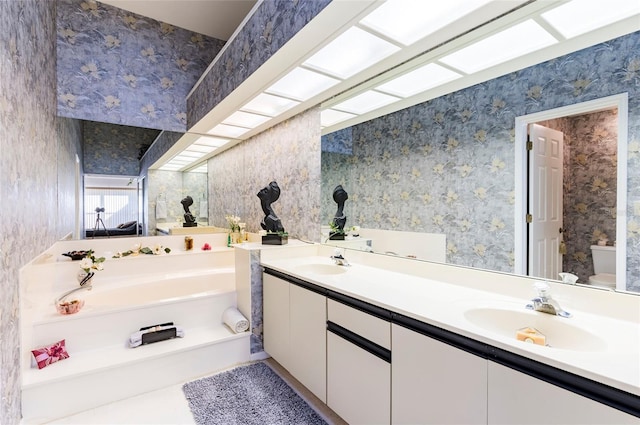 bathroom with a washtub, toilet, and vanity