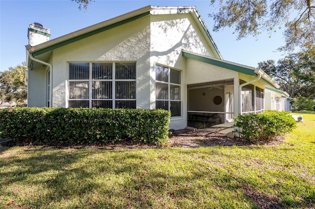 back of property featuring a lawn and a sunroom