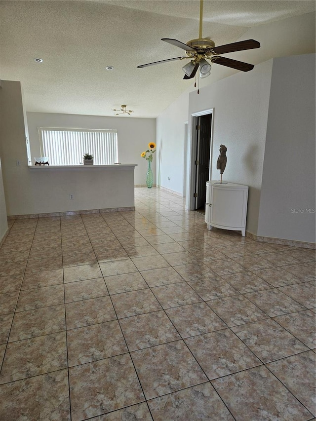 spare room featuring ceiling fan, light tile patterned floors, and a textured ceiling