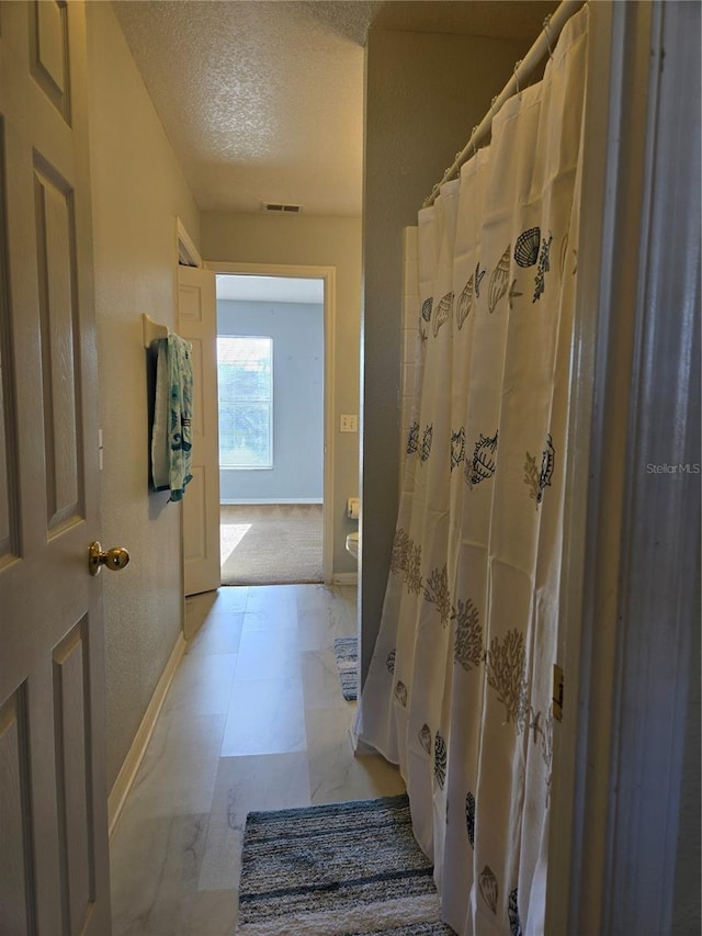 bathroom with a textured ceiling and curtained shower