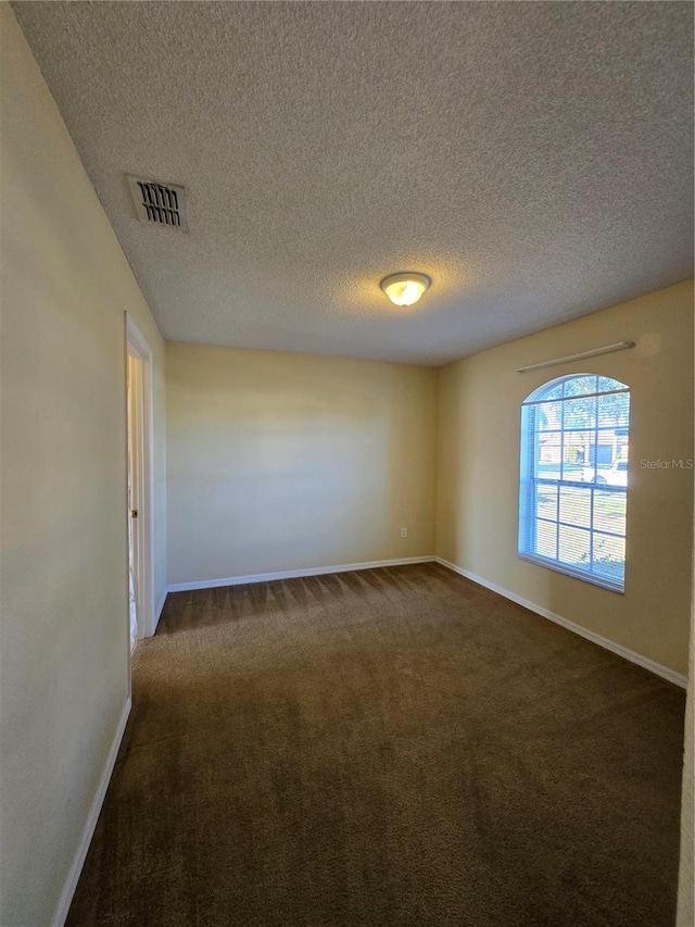 empty room featuring dark carpet and a textured ceiling