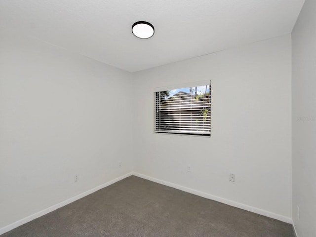 unfurnished room featuring dark carpet