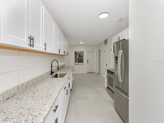 kitchen featuring sink, stainless steel appliances, white cabinets, and light stone counters