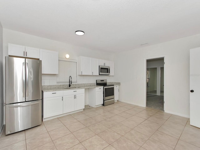 kitchen with appliances with stainless steel finishes, white cabinetry, and sink