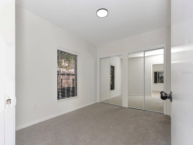 unfurnished bedroom featuring multiple closets and light carpet