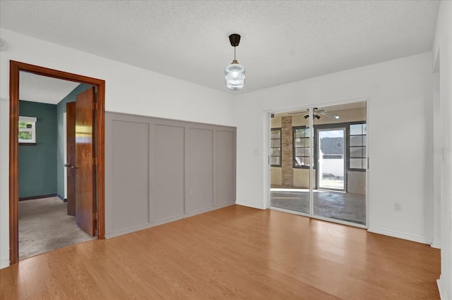 unfurnished room with ceiling fan, a textured ceiling, and light wood-type flooring