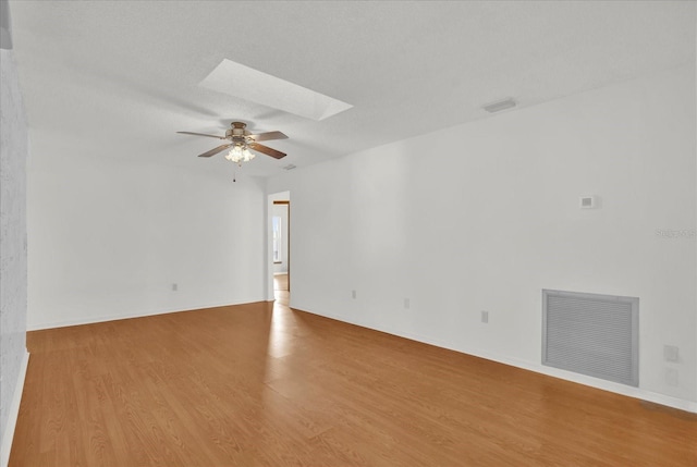 spare room featuring a skylight, ceiling fan, a textured ceiling, and hardwood / wood-style flooring