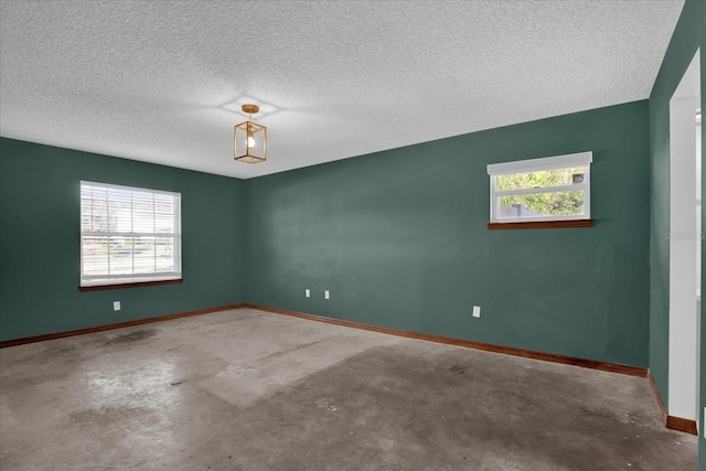 unfurnished room with concrete flooring, a textured ceiling, and plenty of natural light