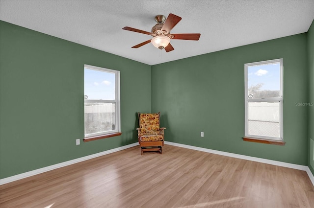 unfurnished room with ceiling fan, light wood-type flooring, and a textured ceiling