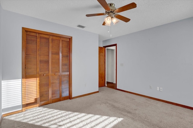 unfurnished bedroom featuring light carpet, a textured ceiling, a closet, and ceiling fan