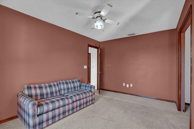 living area featuring a textured ceiling, light colored carpet, and ceiling fan