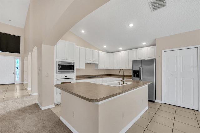 kitchen with white cabinets, sink, an island with sink, appliances with stainless steel finishes, and light tile patterned flooring