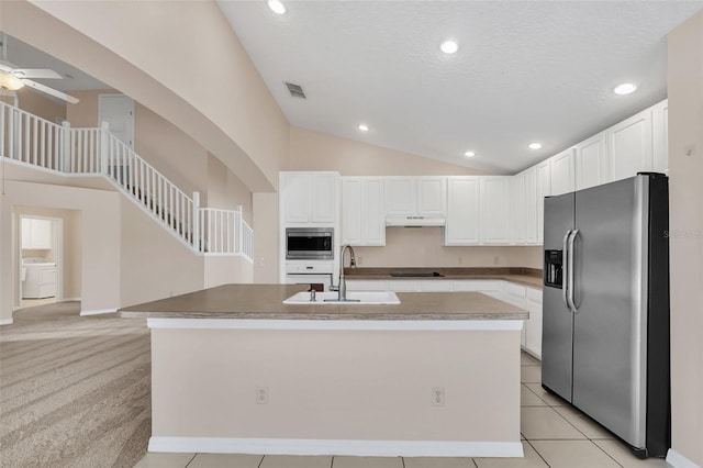 kitchen with light carpet, appliances with stainless steel finishes, a kitchen island with sink, sink, and white cabinetry