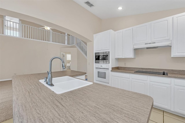 kitchen featuring white cabinetry, black electric cooktop, sink, and white oven