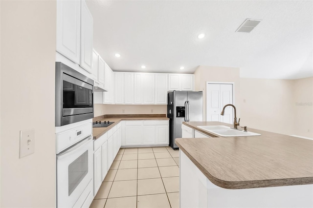 kitchen featuring stainless steel appliances, a kitchen island with sink, sink, white cabinetry, and light tile patterned flooring