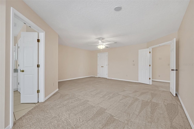 carpeted empty room with ceiling fan and a textured ceiling