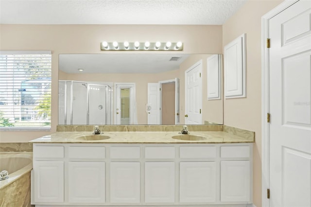 bathroom featuring a textured ceiling, vanity, and shower with separate bathtub