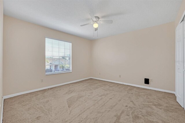 carpeted empty room with ceiling fan and a textured ceiling