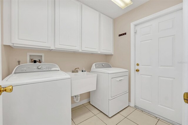 laundry room featuring cabinets, light tile patterned floors, sink, and washing machine and clothes dryer