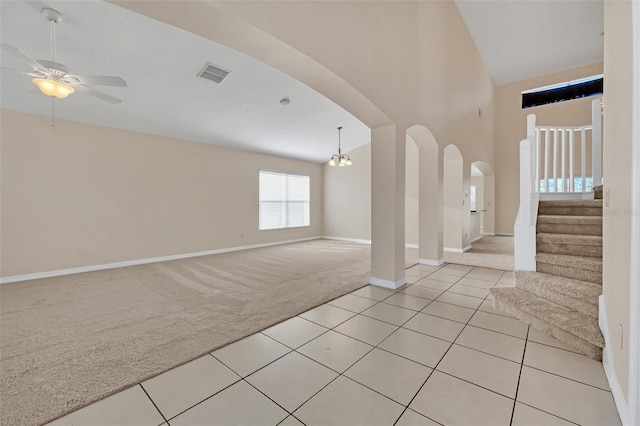 foyer entrance featuring ceiling fan with notable chandelier, light colored carpet, and high vaulted ceiling