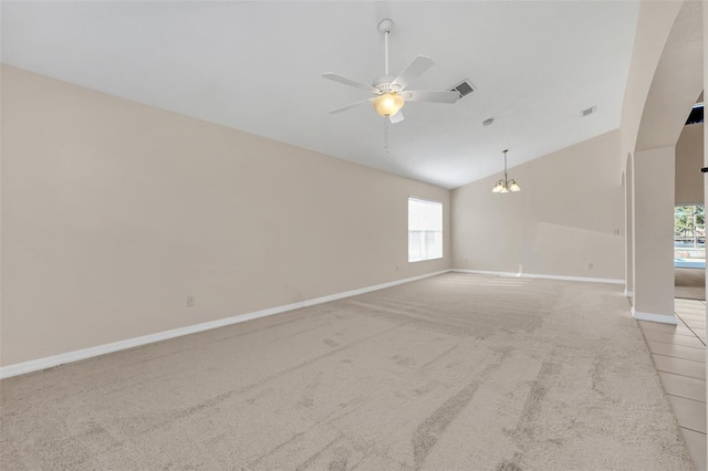 carpeted empty room with ceiling fan with notable chandelier and vaulted ceiling