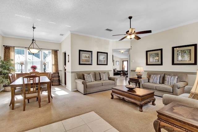 living room with ceiling fan, light colored carpet, ornamental molding, and a textured ceiling