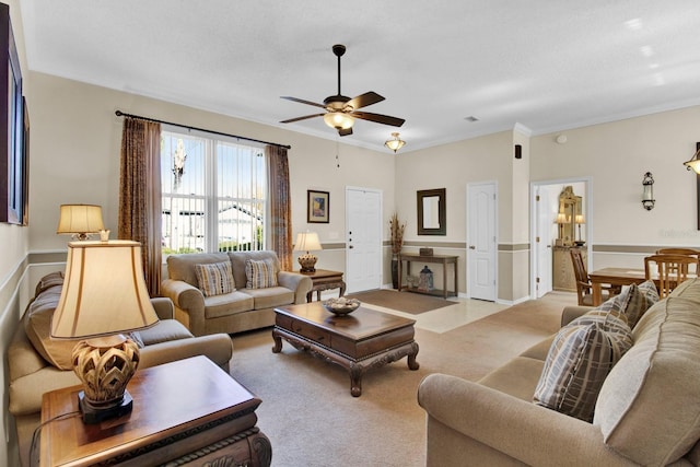 living room with a textured ceiling, ceiling fan, crown molding, and light carpet