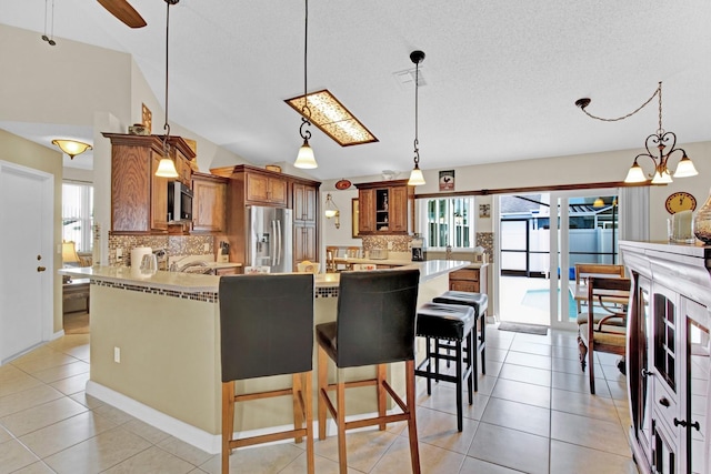 kitchen with backsplash, a kitchen bar, light tile patterned floors, and stainless steel appliances