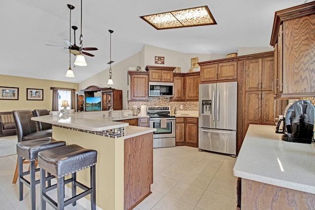 kitchen featuring a breakfast bar, pendant lighting, vaulted ceiling, and appliances with stainless steel finishes