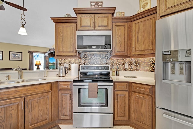 kitchen featuring backsplash, sink, ceiling fan, appliances with stainless steel finishes, and decorative light fixtures