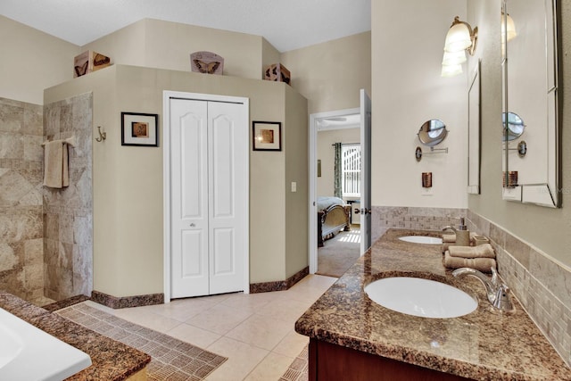 bathroom with tile patterned floors, vanity, a textured ceiling, and tiled shower